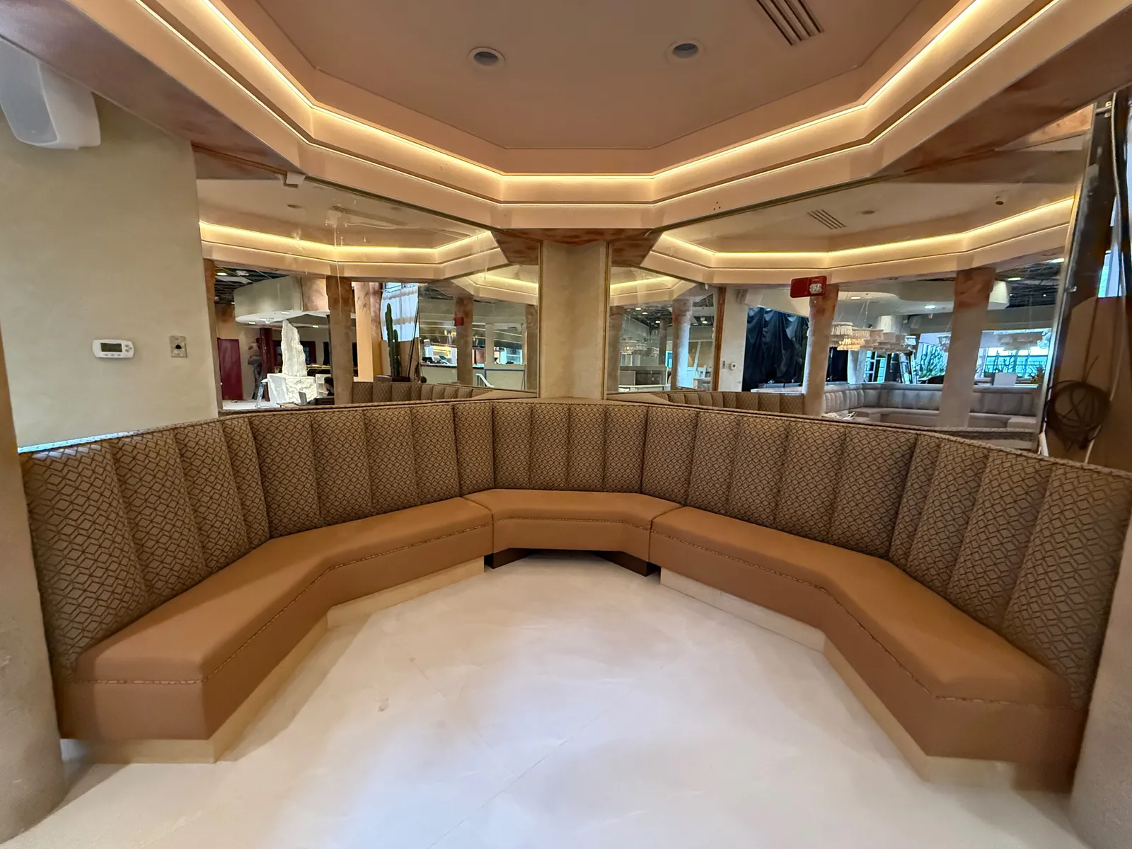 Large curved banquette in tan vinyl with channel backs and diamond-stitched end panels in a Florida dining room