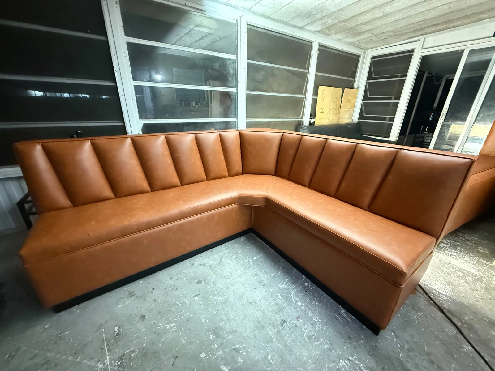 L-shaped cognac vinyl booth with tall channel back, ready for delivery