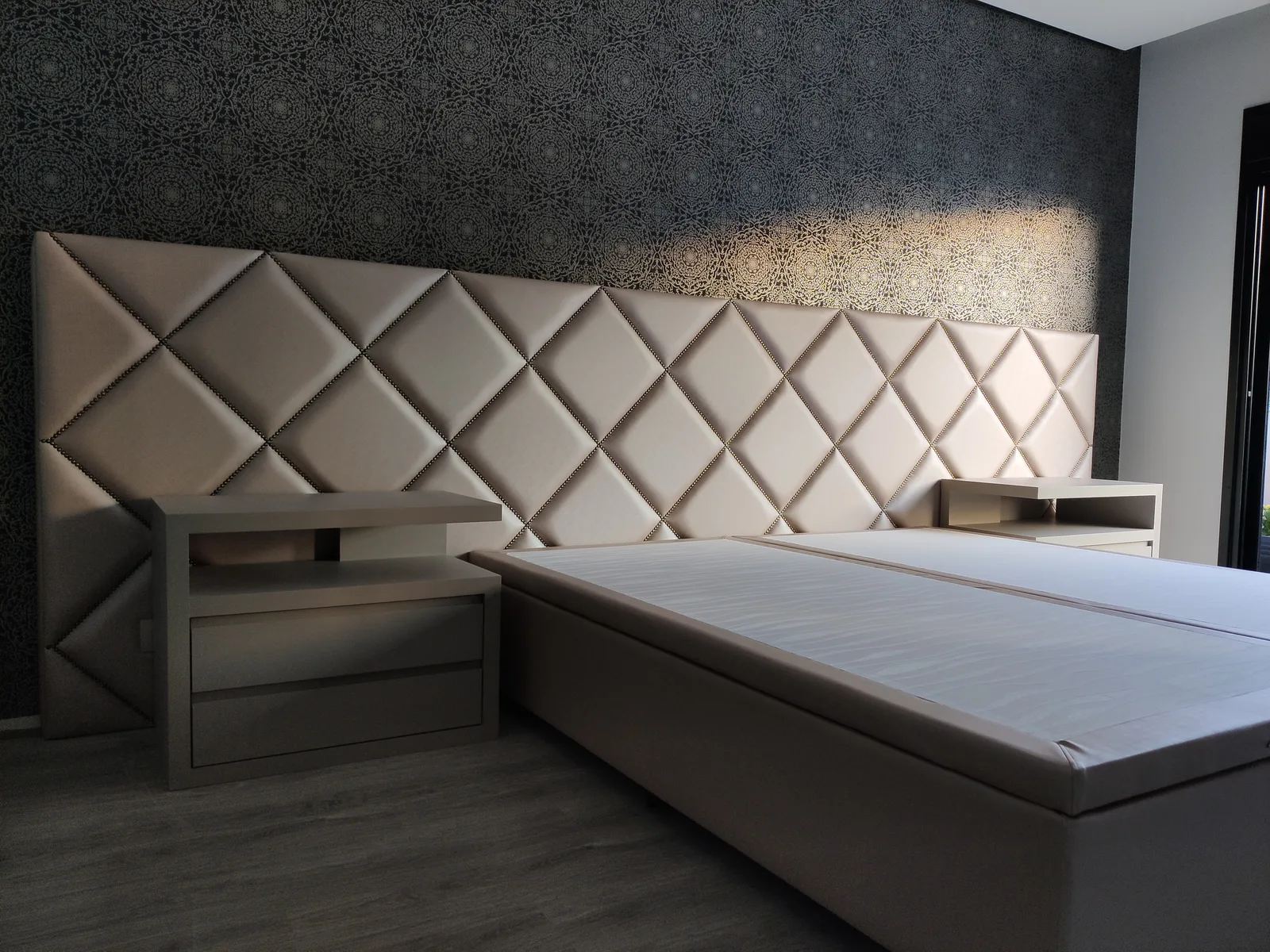 Painel estofado de losangos com tachas em parede de papel escuro