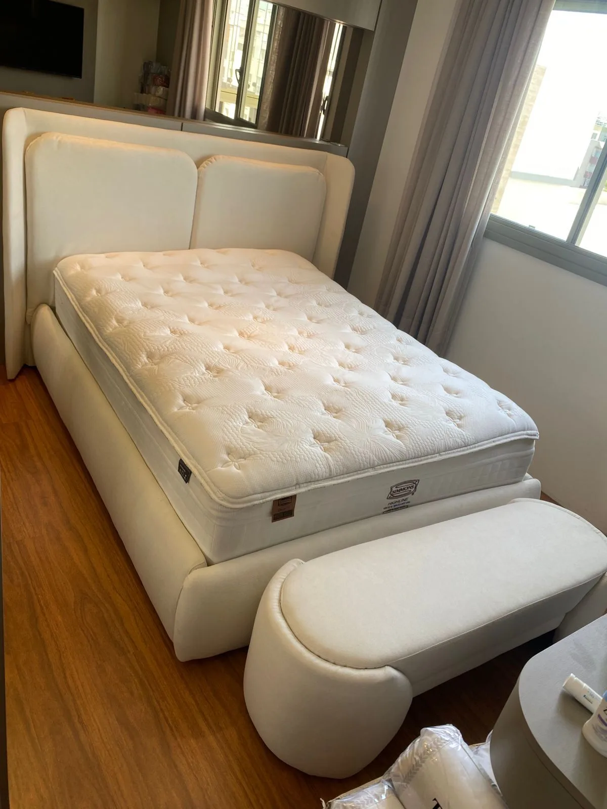 Banco orgânico moderno de linhas curvas ao pé de cama branca