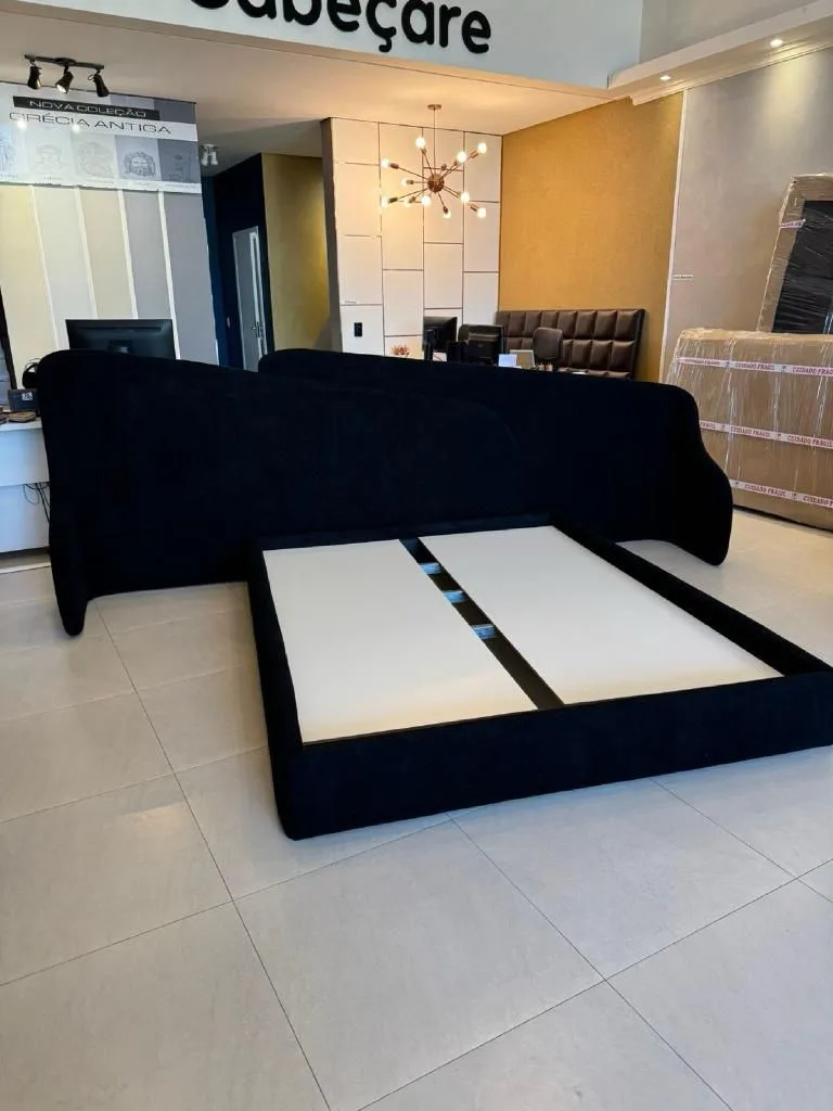 Cama preta moderna com abas laterais esculturais no showroom da Cabeçare