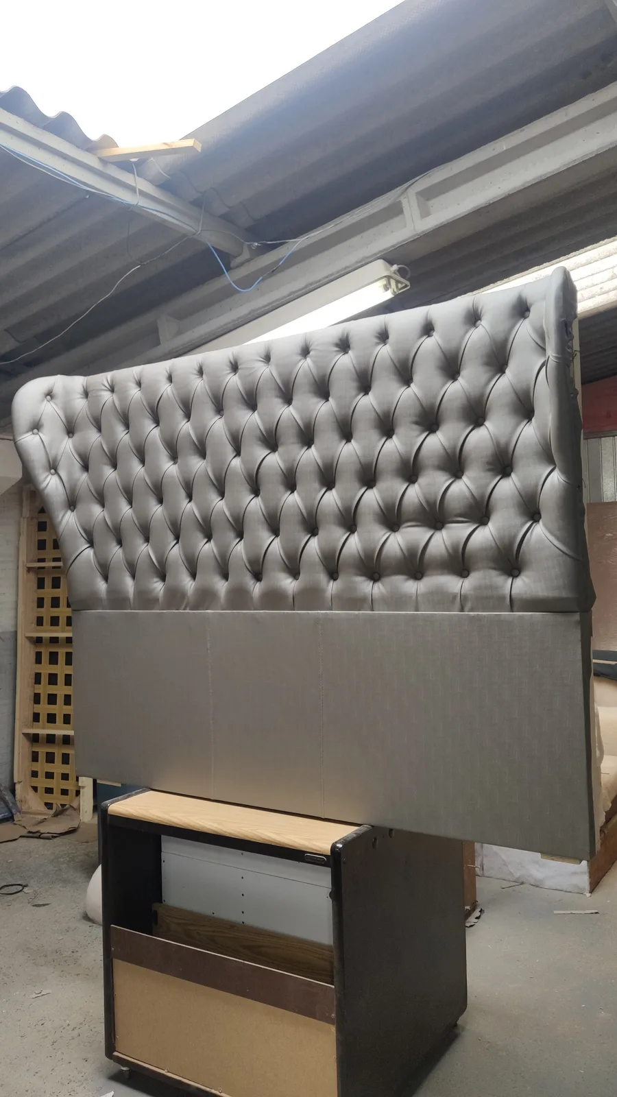 Silver tufted wingback headboard being finished at the atelier