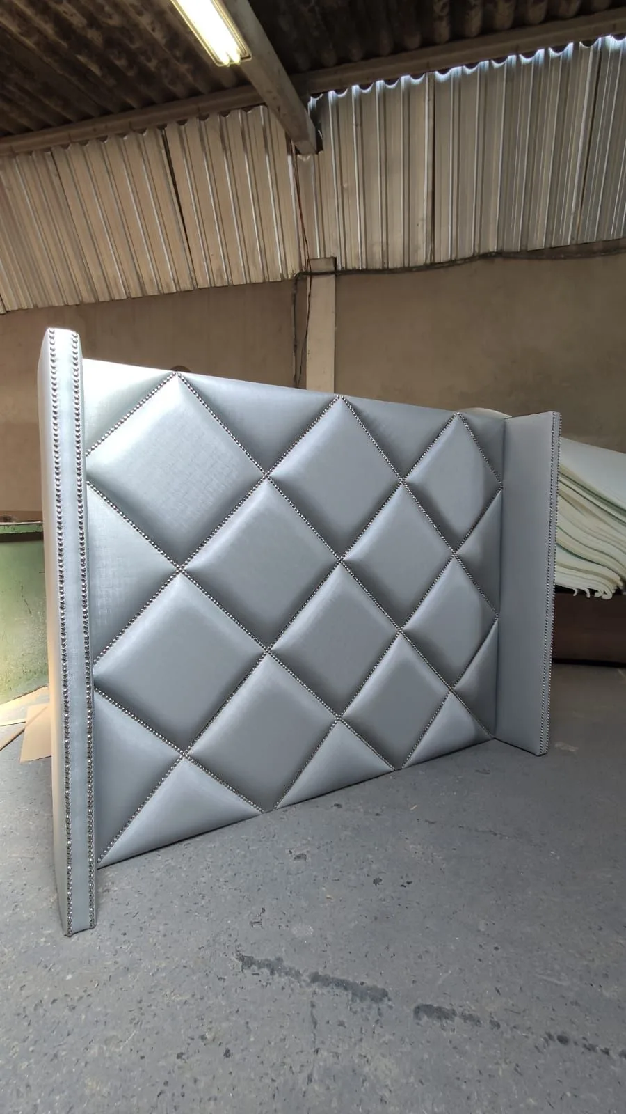 Cabeceira com orelhas em matelassê de losangos com tachas, acabamento prata