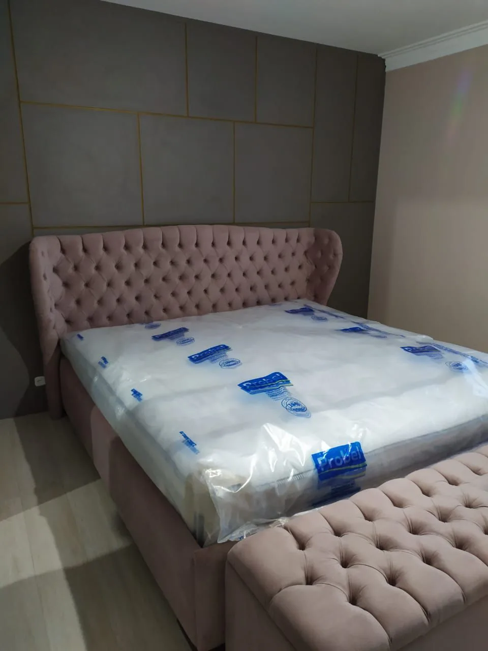 Cama com cabeceira de abas capitonê rosa e recamier combinando instalada no quarto da cliente